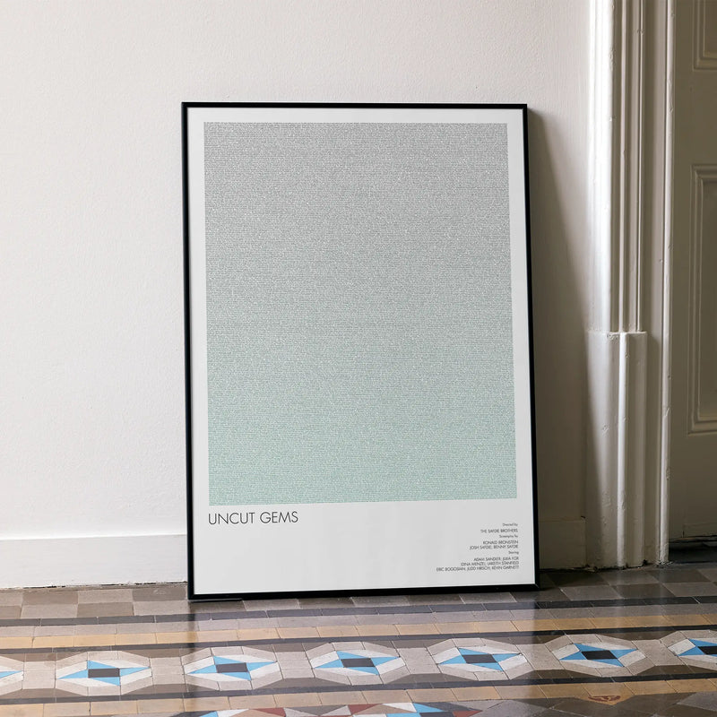 A framed Uncut Gems movie script poster leaning against a wall in a minimalist interior.