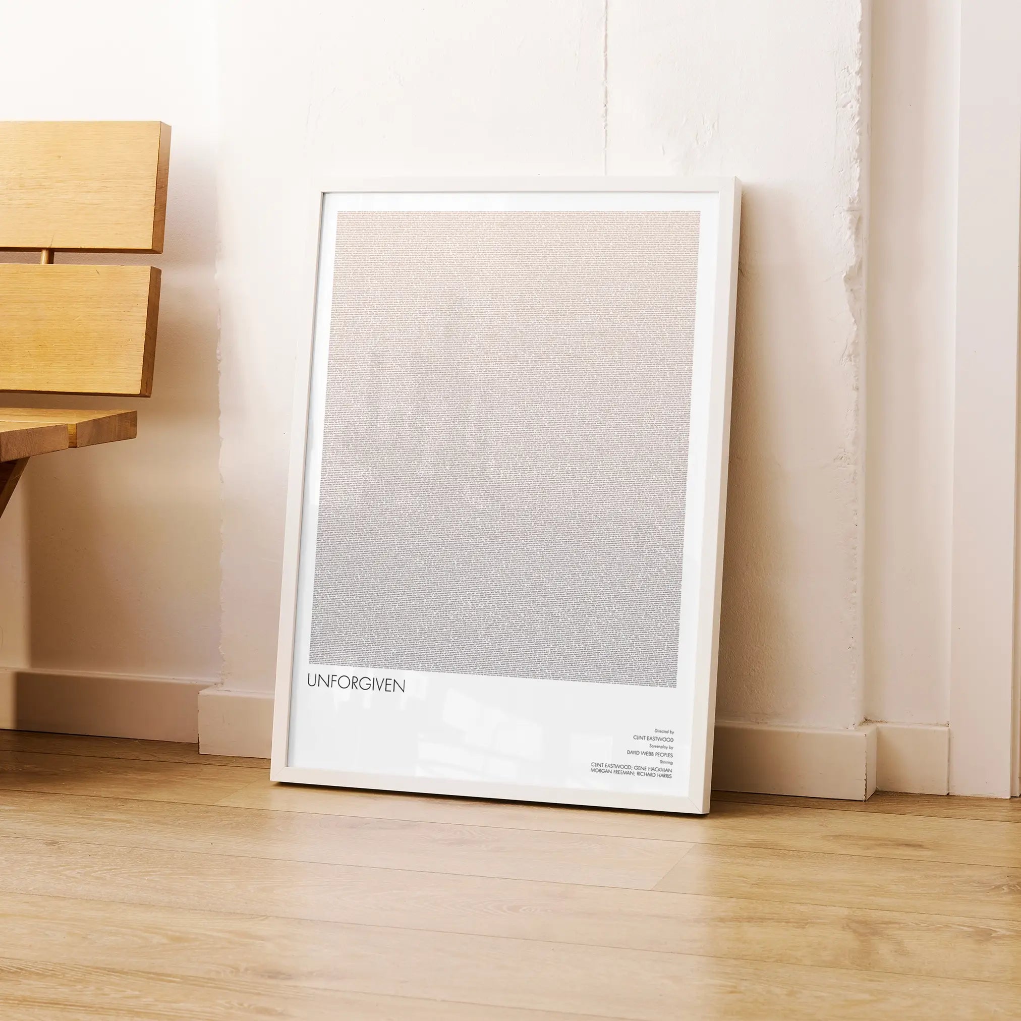A framed Unforgiven movie script poster leaning against a wall in a modern interior.