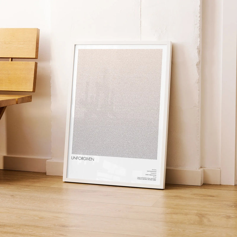 A framed Unforgiven movie script poster leaning against a wall in a modern interior.