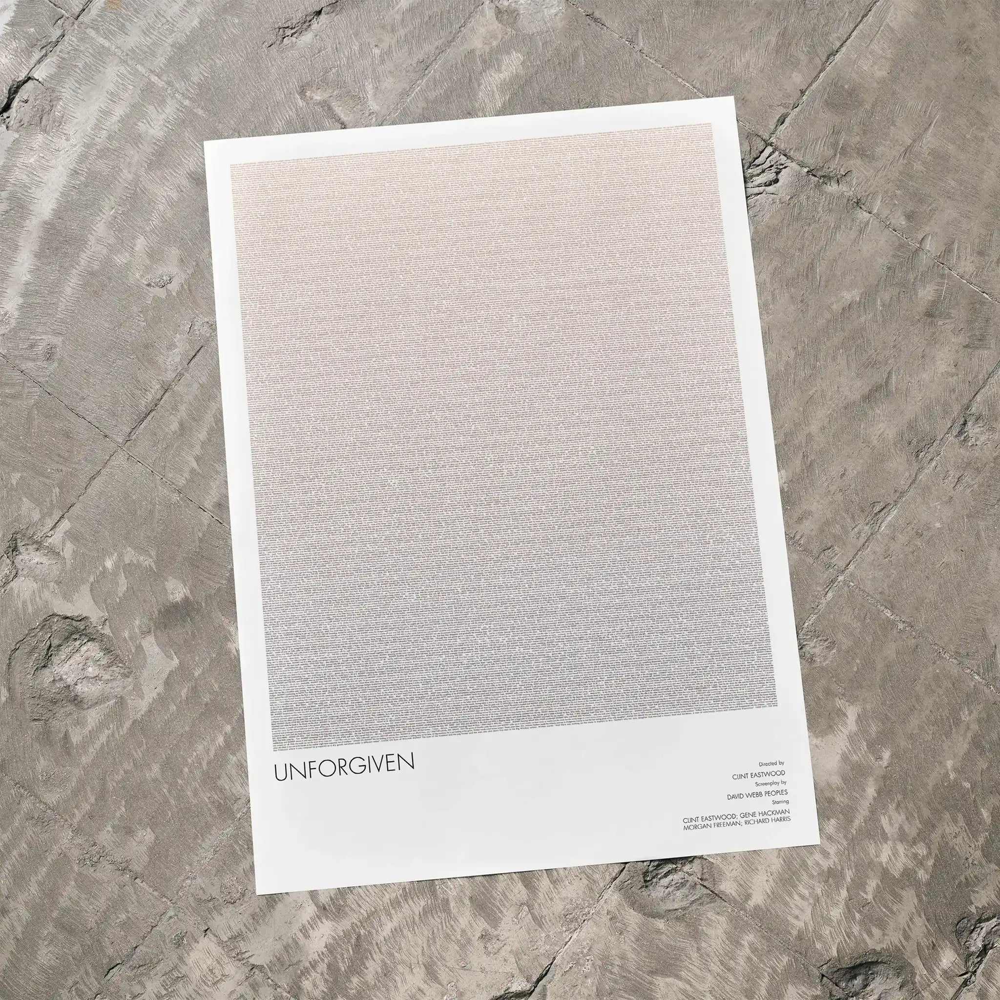 A Unforgiven movie script poster laid flat on a textured floor surface.