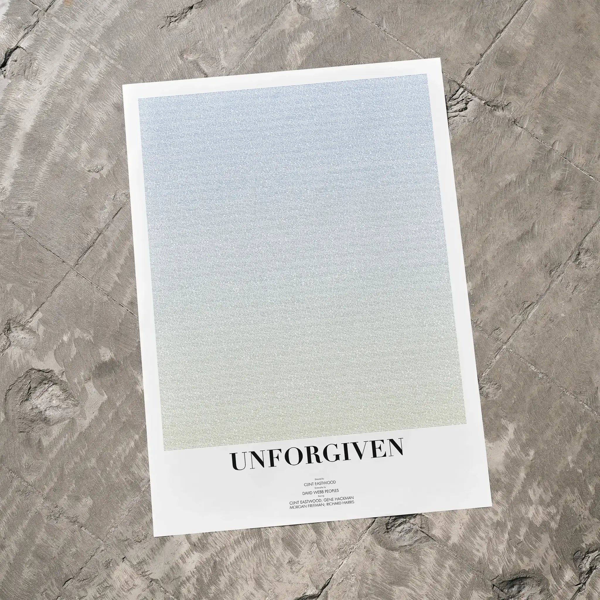 A Unforgiven movie script poster laid flat on a textured floor surface.