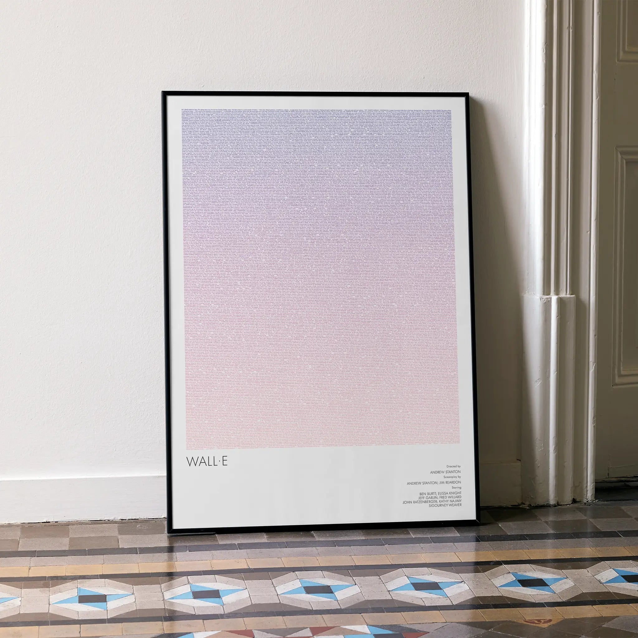 A framed WALL·E movie script poster leaning against a wall in a minimalist interior.