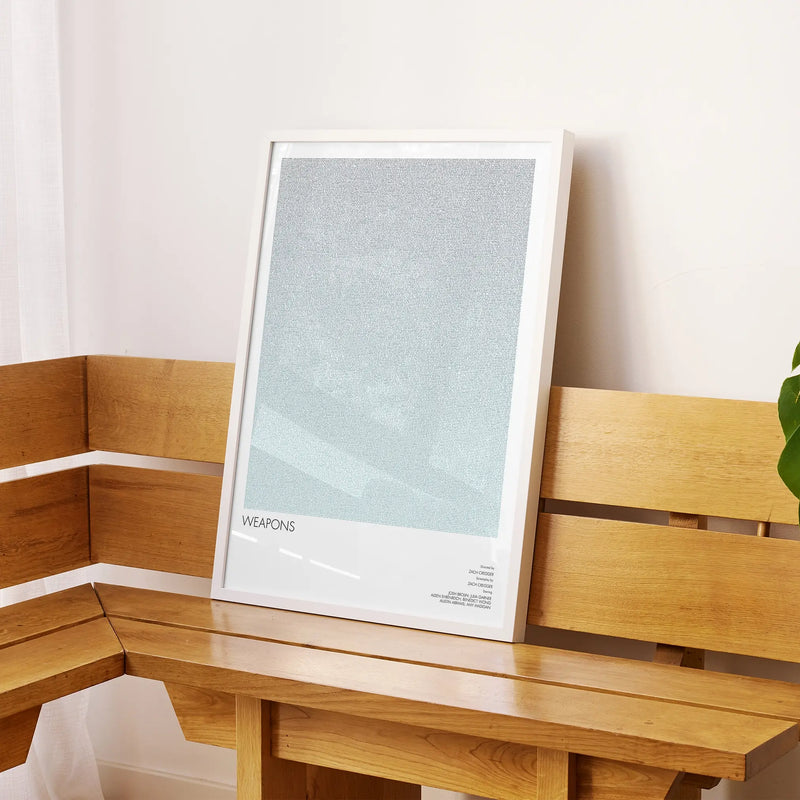 A framed Weapons movie script poster displayed on a sideboard in a contemporary space.
