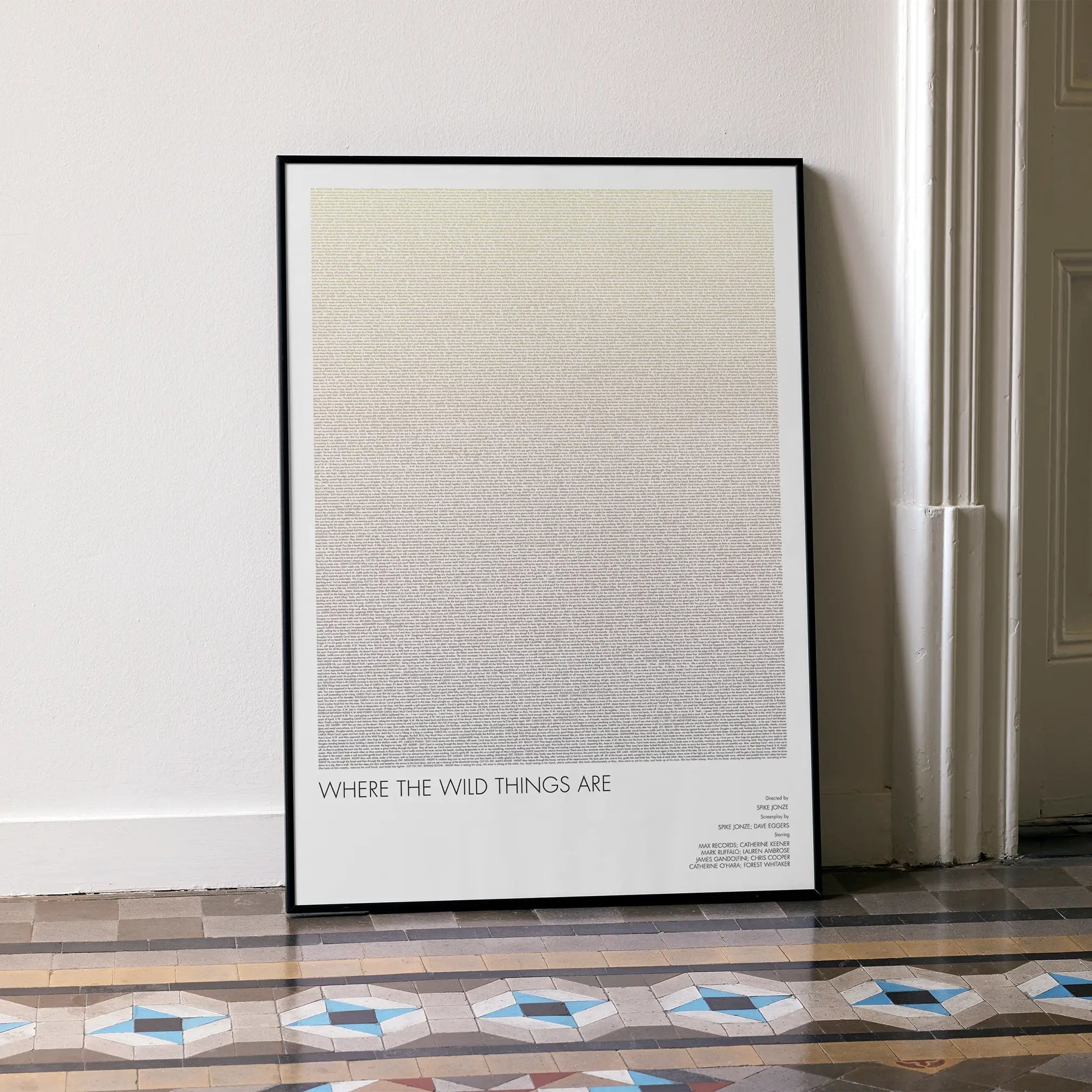 A framed Where the Wild Things Are movie script poster leaning against a wall in a minimalist interior.