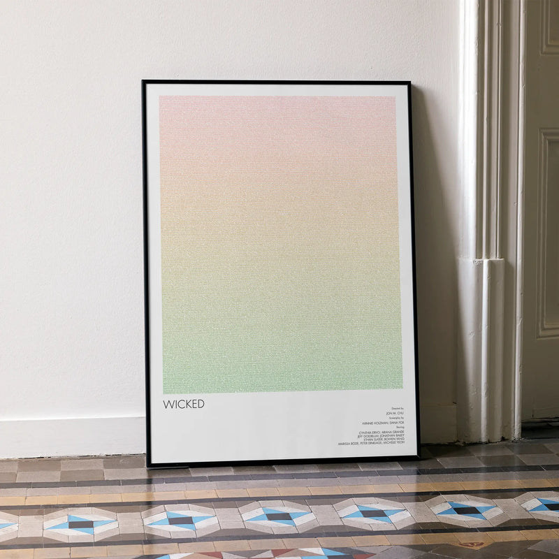 A framed Wicked movie script poster leaning against a wall in a minimalist interior.