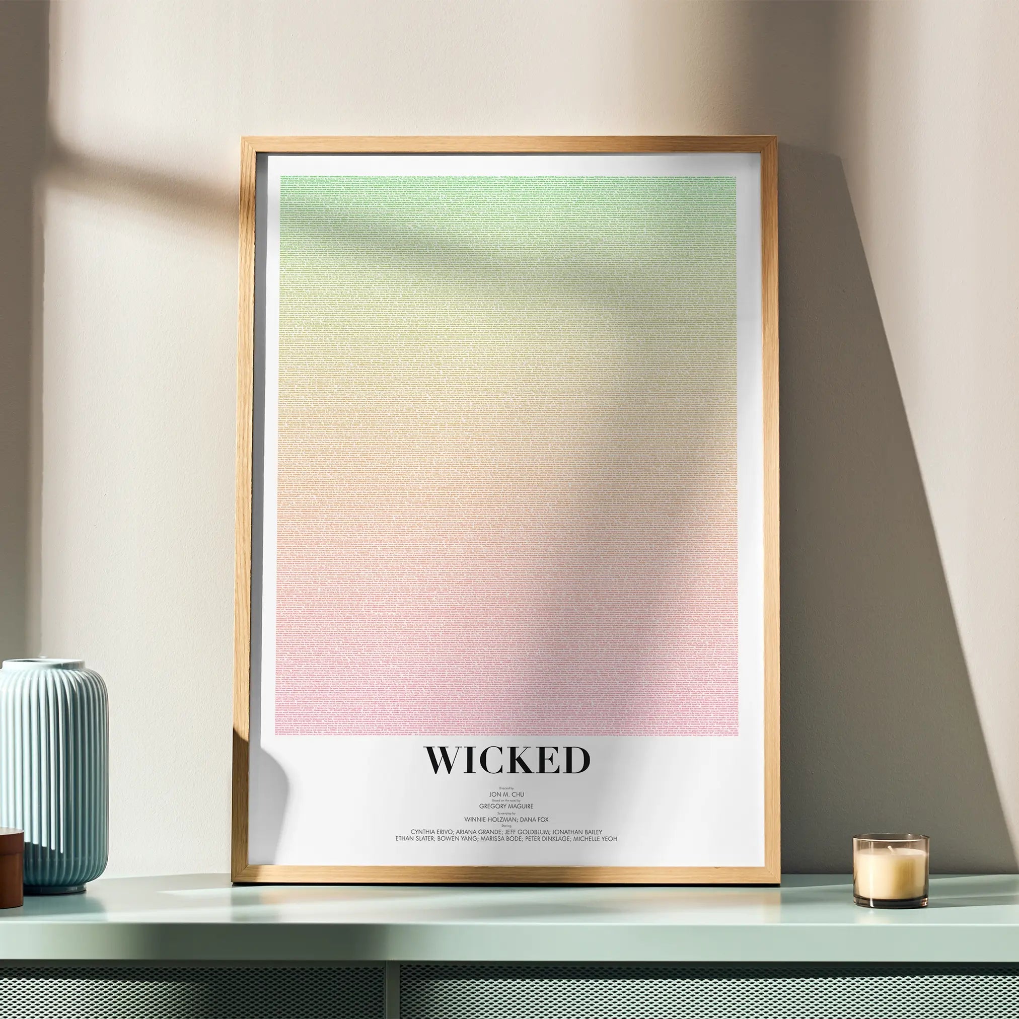 Framed poster with gradient design and 'Wicked' text on a table with decorative items.