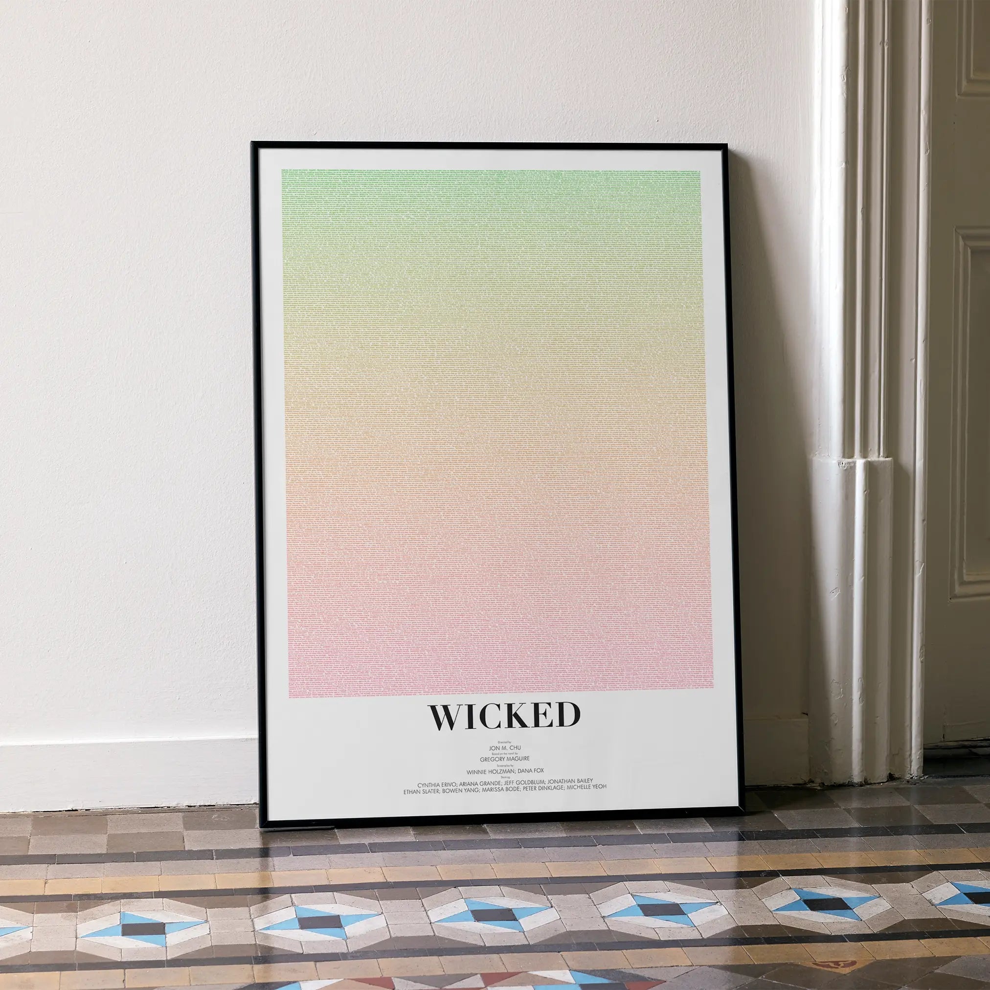Wicked movie poster in a black frame leans on wall.