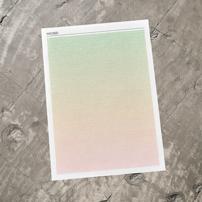 A Wicked movie script poster laid flat on a textured floor surface.