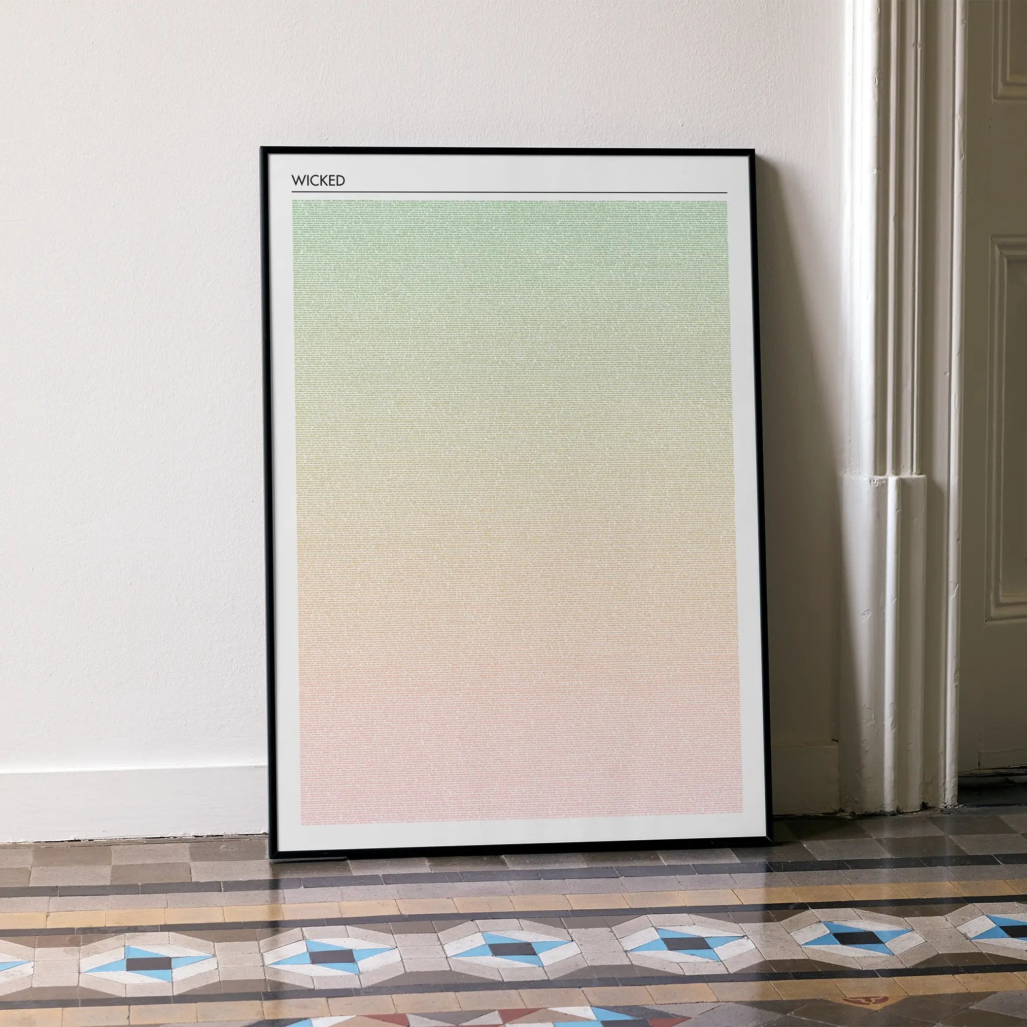 A framed Wicked movie script poster leaning against a wall in a minimalist interior.