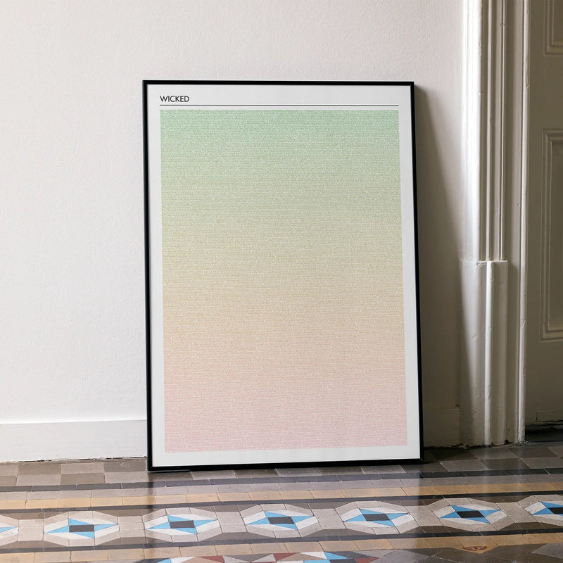 A framed Wicked movie script poster leaning against a wall in a minimalist interior.