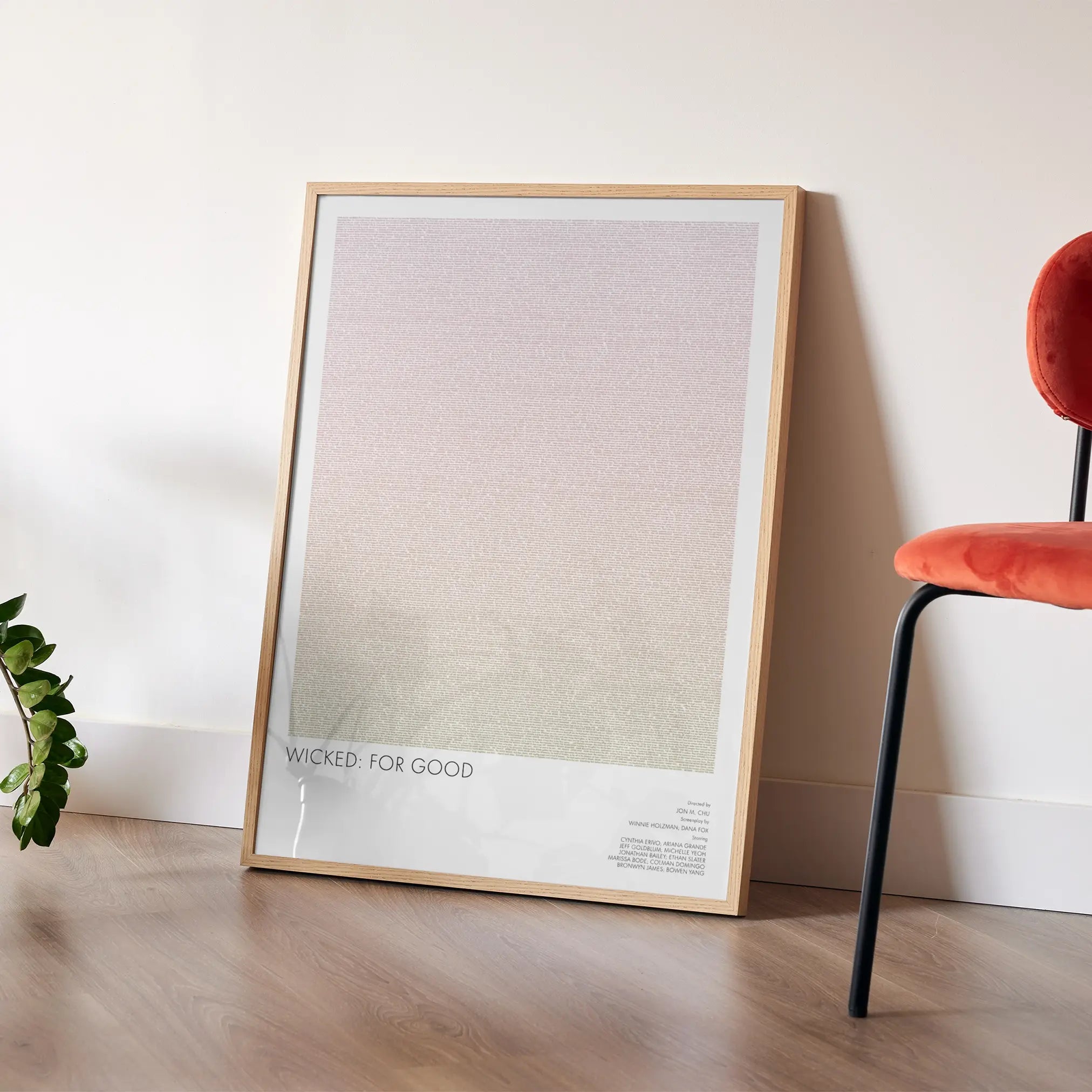 A framed Wicked for Good movie script poster leaning against a wall in a modern interior.